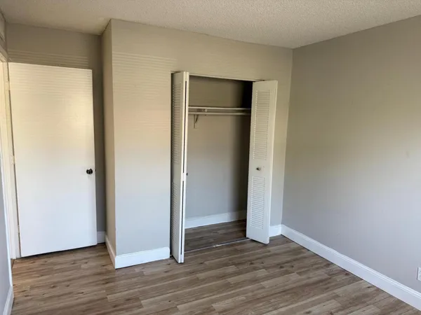 a view of an empty room with wooden floor and closet