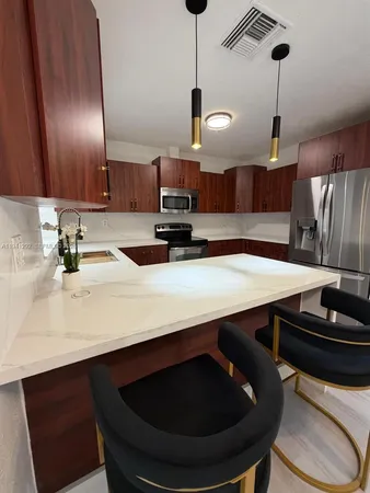 a kitchen with stainless steel appliances a sink a microwave a dining table and chairs
