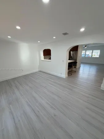 an empty room with wooden floor and entrance