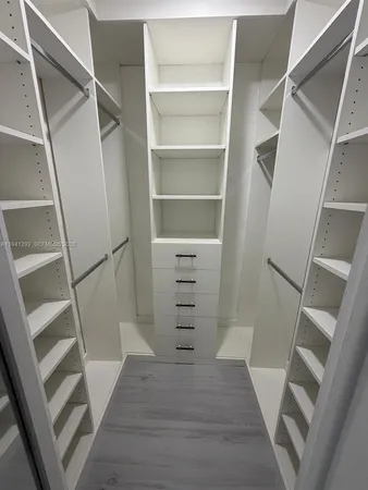 a view of walk in closet with wooden floor and stairs