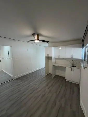an empty room with wooden floor sink and cabinet