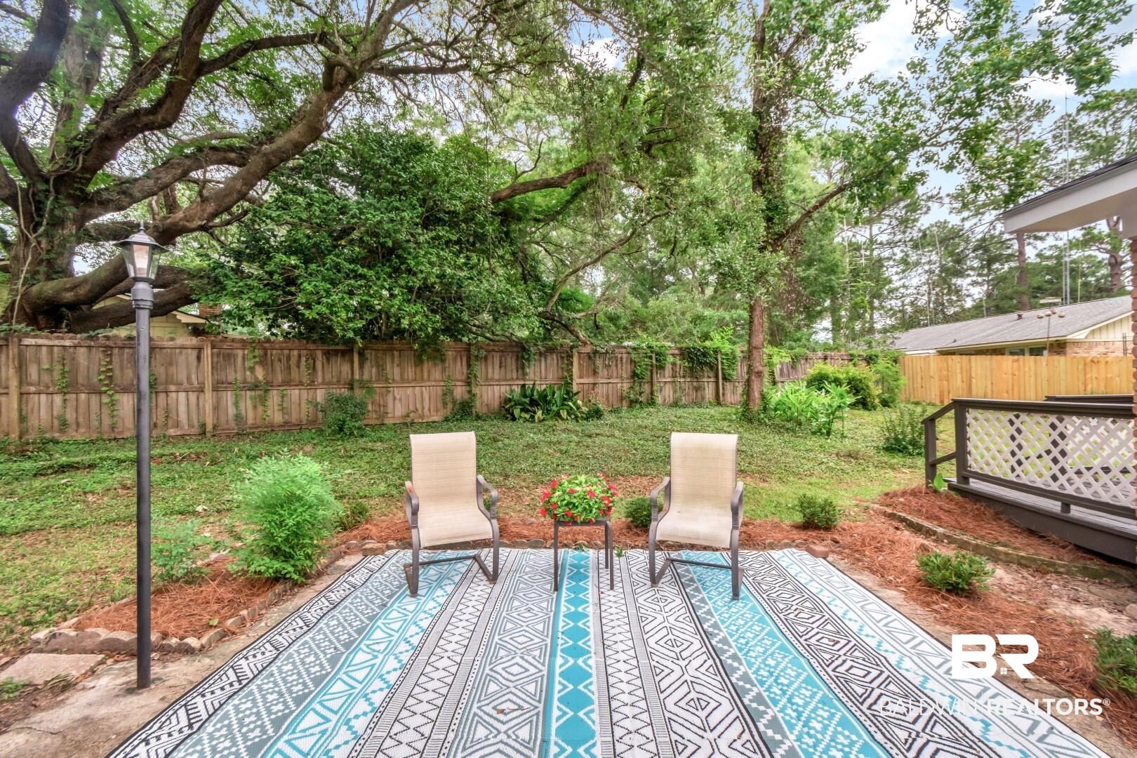 5217 Perin Road Mobile, AL 36693 - Photo 31 of 45 Private backyard featuring a concrete patio, mature trees, a wooden privacy fence, and a built-in deck with lattice railing