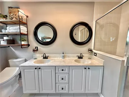 a bathroom with a toilet a double vanity sink and a mirror