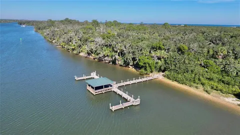 a view of a lake with lawn chairs under an umbrella