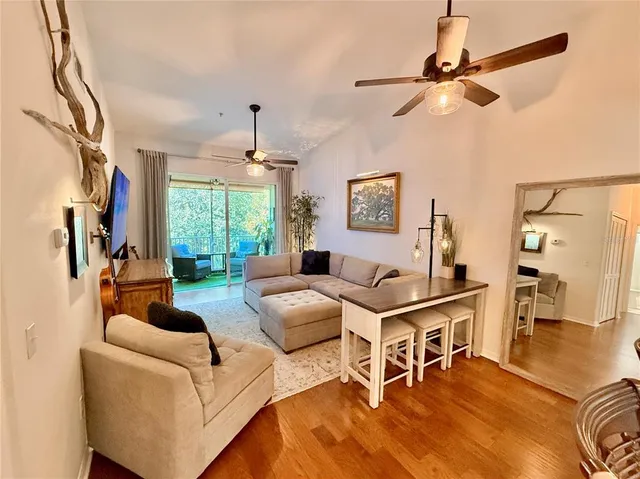 a living room with furniture a ceiling fan a rug and a window