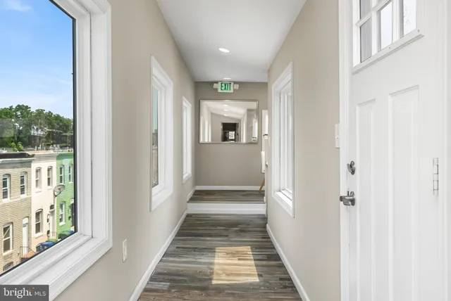 a living room with stainless steel appliances kitchen island granite countertop a refrigerator a stove a sink dishwasher with wooden floor and cabinets