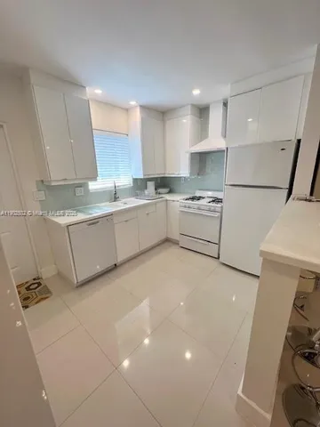 a large kitchen with stainless steel appliances a sink a stove a refrigerator and a cabinets