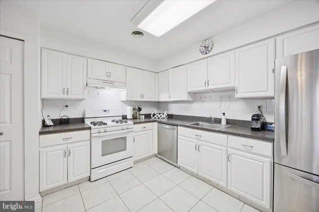 a kitchen with granite countertop white cabinets and white appliances