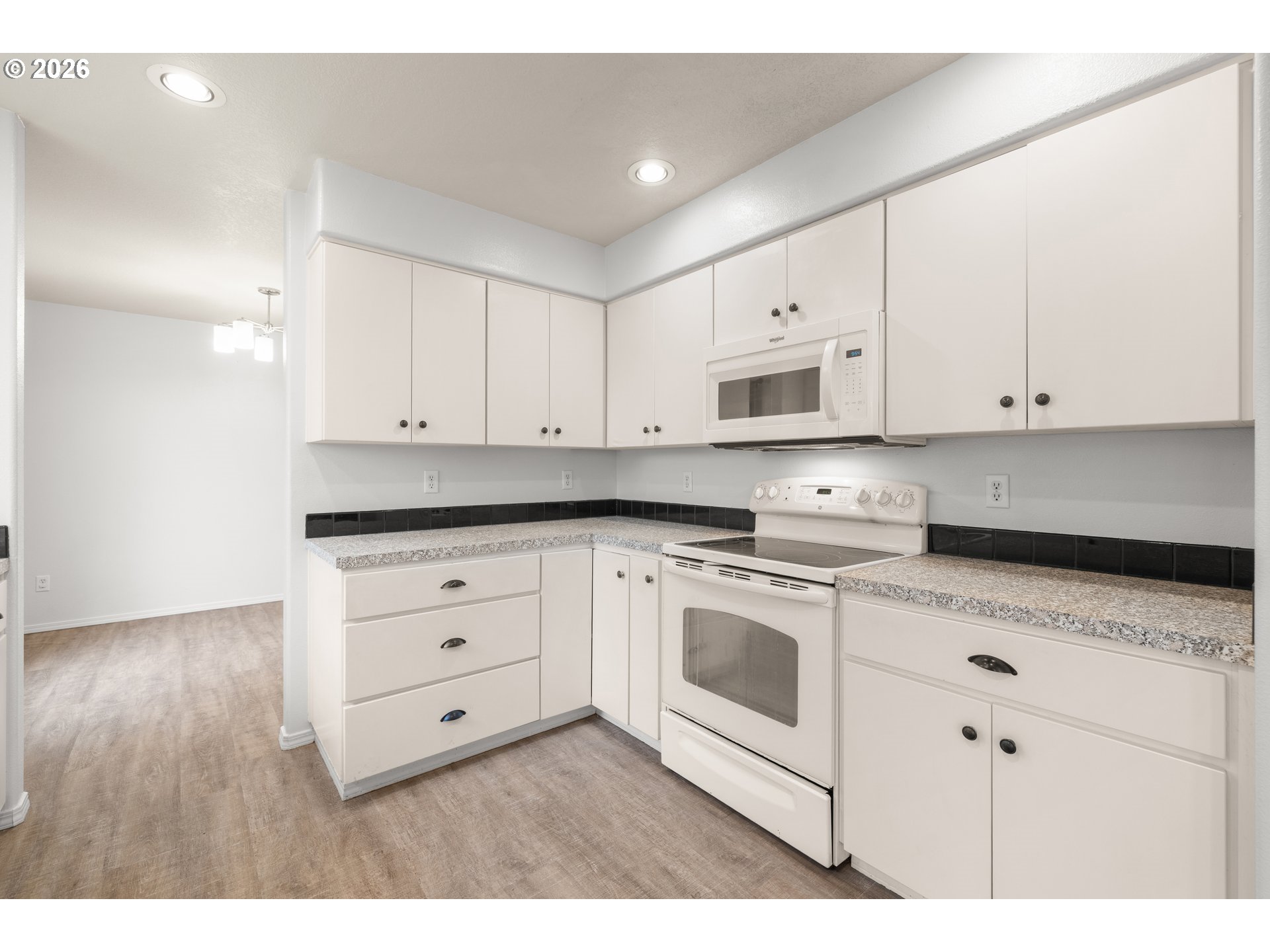 5572 Northwest 165th Place Portland, OR 97229 - Photo 12 of 48 a kitchen with granite countertop white cabinets and white appliances