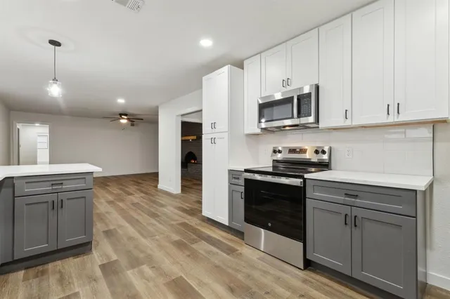 a kitchen with stainless steel appliances granite countertop a stove a sink and a microwave