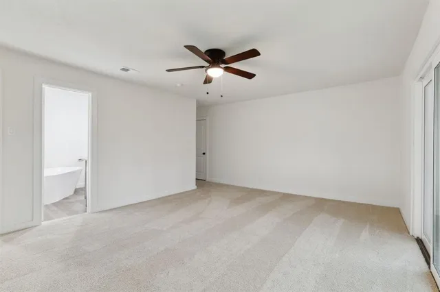an empty room with a ceiling fan and a window