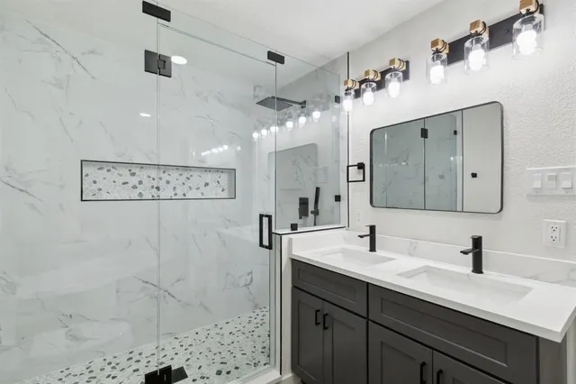 a bathroom with a double vanity sink mirror and shower