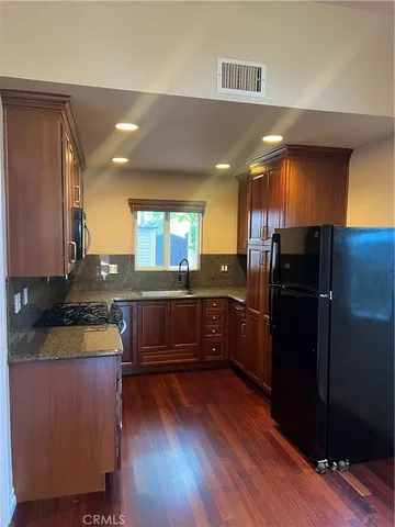 a kitchen with granite countertop a refrigerator a stove and wooden floor