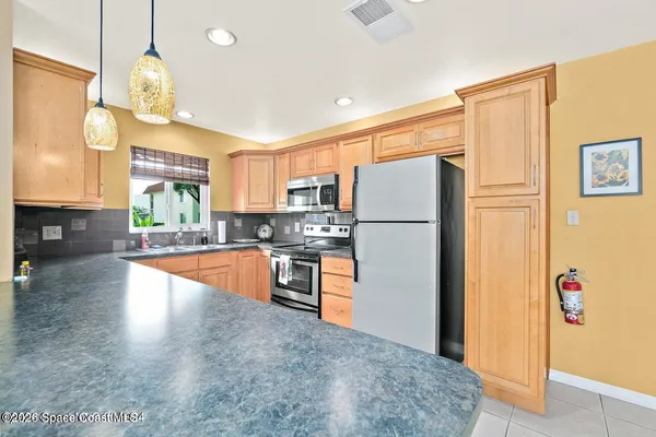 a kitchen with granite countertop a refrigerator a stove a sink dishwasher a oven a dining table and chairs with wooden floor