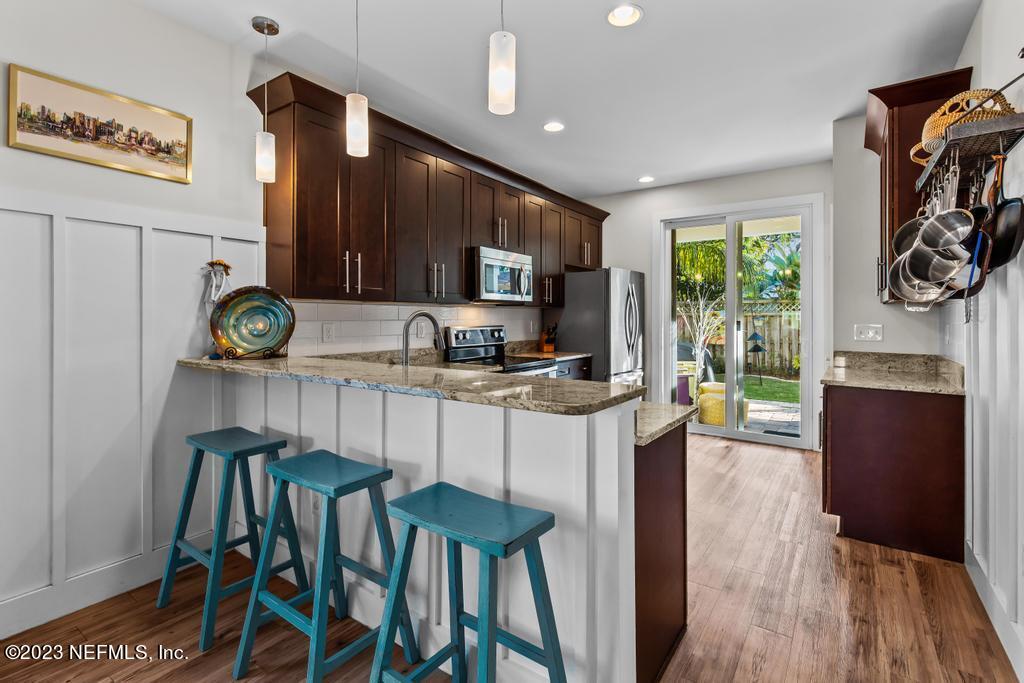 311 E Street St. Augustine, FL 32080 - Photo 10 of 40 a kitchen with stainless steel appliances kitchen island granite countertop a table chairs and a refrigerator