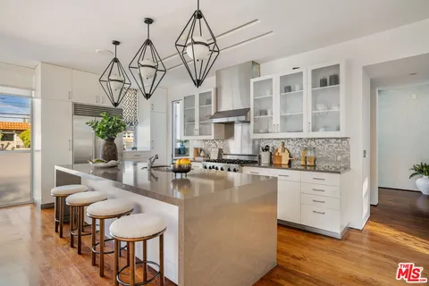 a kitchen with stainless steel appliances granite countertop a table and chairs in it