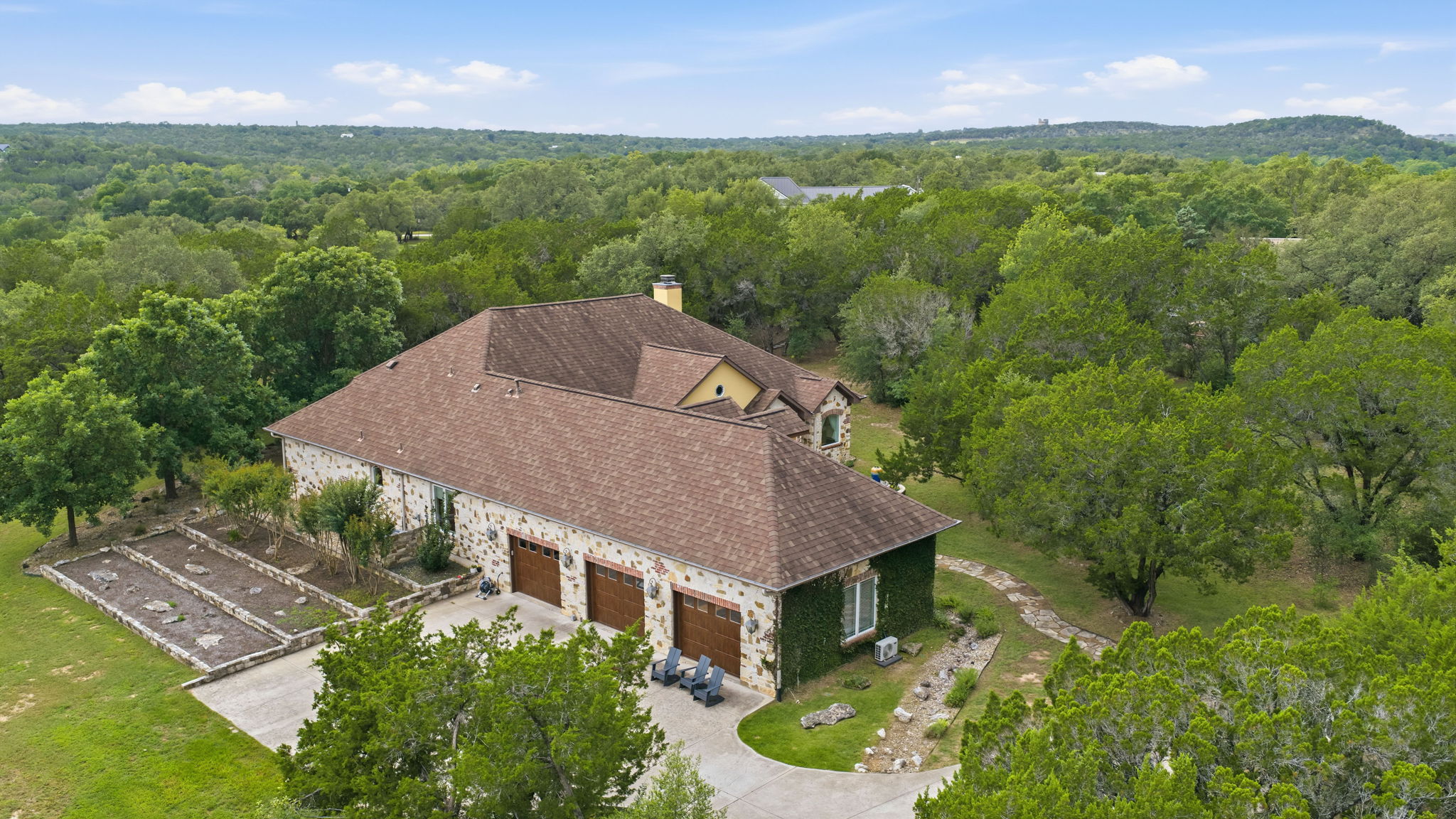 8121 Bluff Trail Austin, TX 78737 - Photo 34 of 40 An aerial perspective reveals a private hillside estate nestled amidst lush, verdant trees.