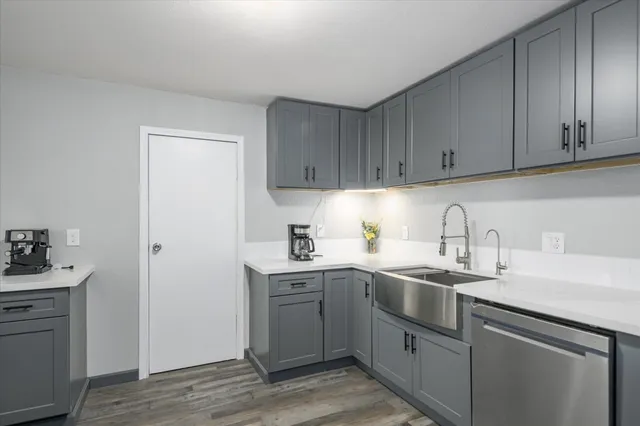 a kitchen with a sink dishwasher and cabinets with wooden floor