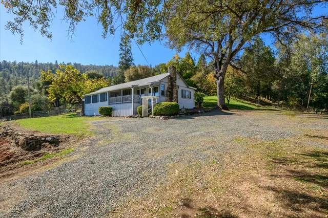 a view of house with outdoor space and trees in the background