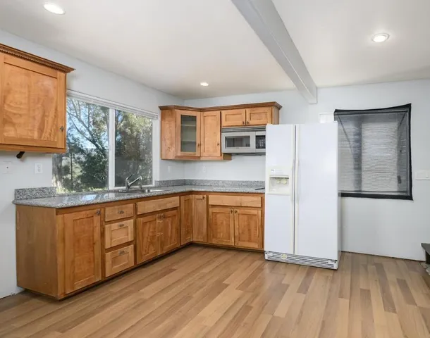 a kitchen with stainless steel appliances granite countertop a sink a microwave cabinets and a window