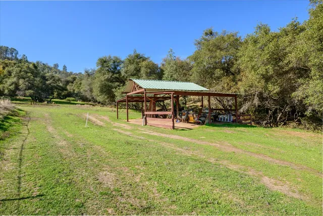 an aerial view of residential house with outdoor space and trees all around