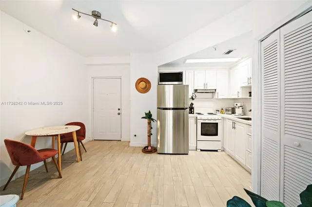 a kitchen with a refrigerator a stove top oven a sink dishwasher and white cabinets with wooden floor