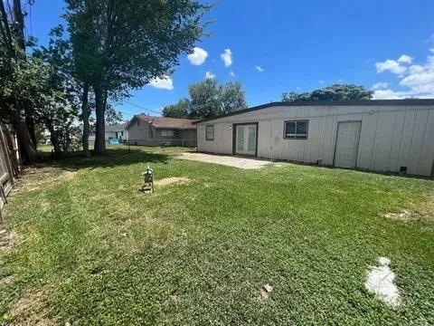 a backyard of a house with plants and large tree