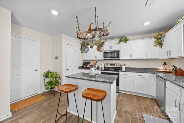 a kitchen with stainless steel appliances granite countertop a stove a sink dishwasher a dining table and chairs with wooden floor