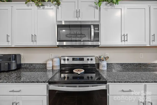 a kitchen with stainless steel appliances granite countertop a refrigerator a sink and white cabinets