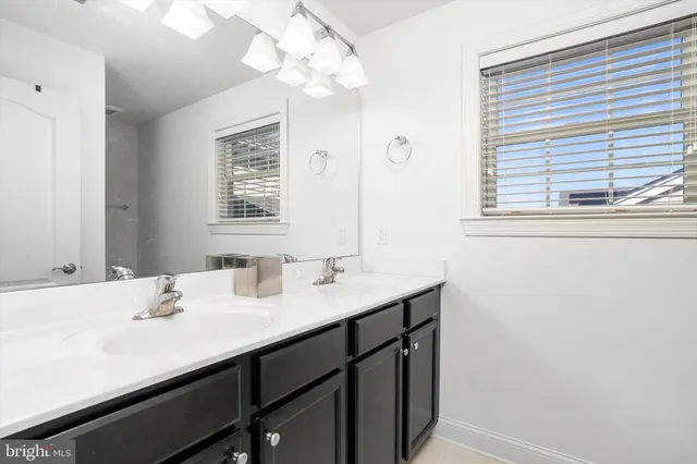 a bathroom with a sink a large mirror and a window