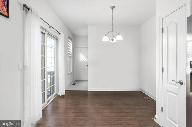 a view of a hallway with chandelier and wooden floor