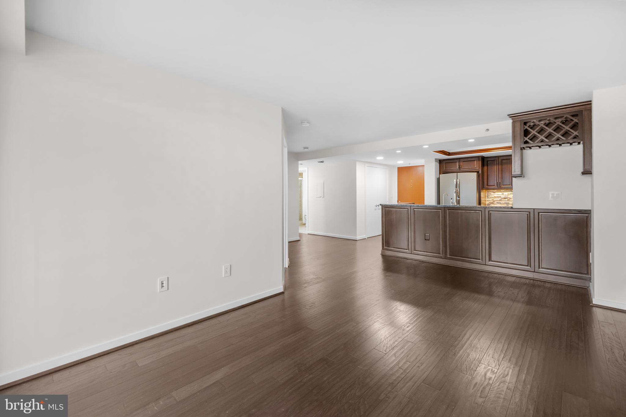 1275 25th Street Northwest, Unit 701 Washington, DC 20037 - Photo 10 of 36 an empty room with wooden floor and kitchen view