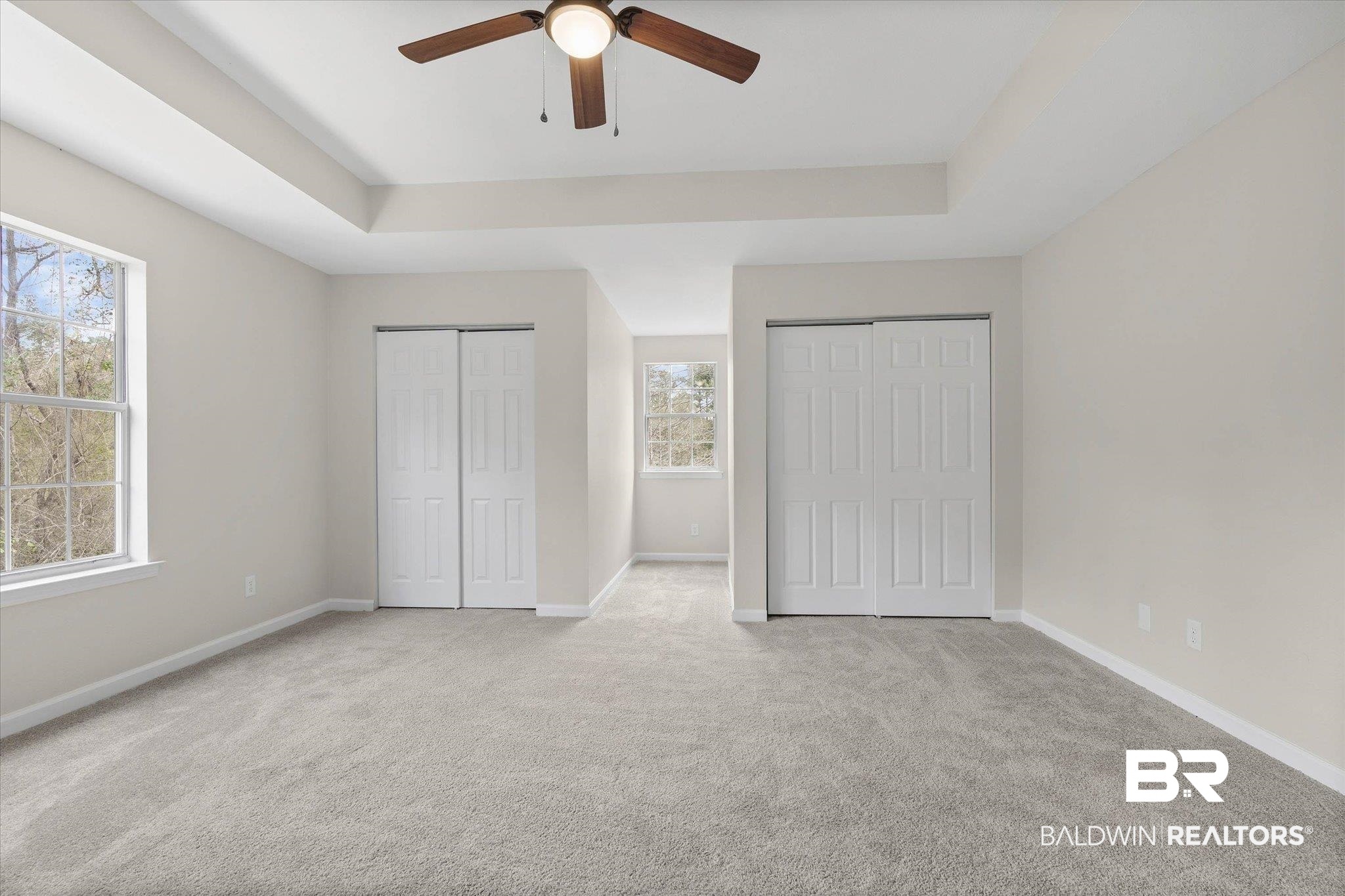 106 Melanie Loop Daphne, AL 36526 - Photo 22 of 45 Unfurnished bedroom featuring two closets, a tray ceiling, light carpet, and a ceiling fan