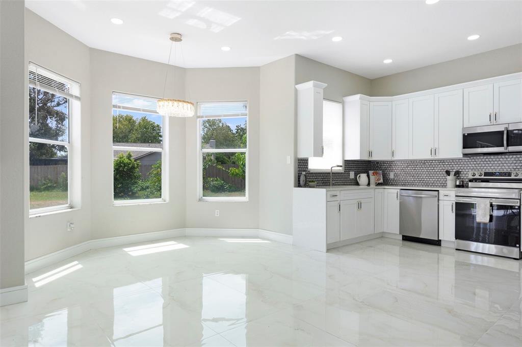 2306 Colusa Lane Valrico, FL 33596 - Photo 13 of 50 a large white kitchen with granite countertop a stove a sink a window and white cabinets