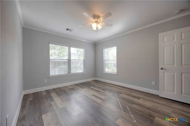 a view of an empty room with wooden floor and a window