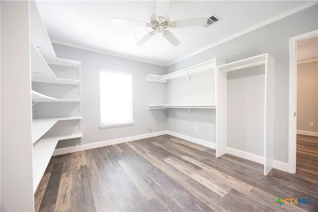 a view of empty room with wooden floor and fan