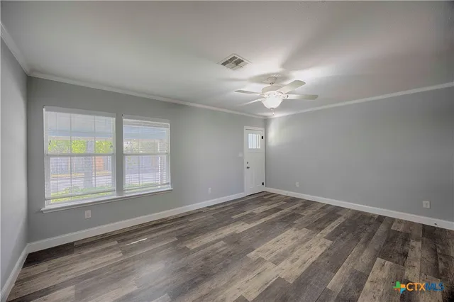 an empty room with windows and ceiling fan