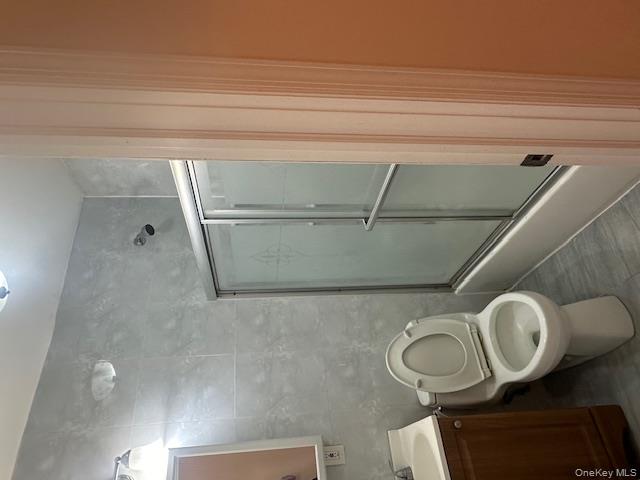 239-13 86th Avenue Queens, NY 11426 - Photo 5 of 12 Bathroom featuring shower / bath combination with glass door, vanity, and tile walls