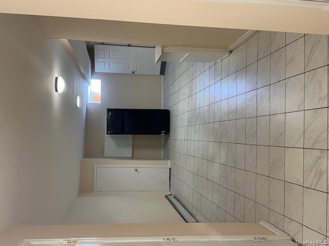 239-13 86th Avenue Queens, NY 11426 - Photo 10 of 12 Unfurnished room featuring a baseboard radiator and light tile patterned floors