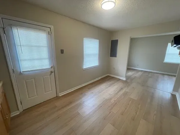 an empty room with wooden floor and windows