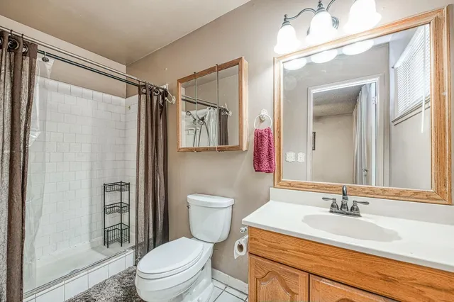 a bathroom with a granite countertop sink toilet a mirror a vanity and shower
