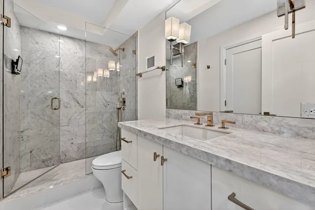 a bathroom with a granite countertop sink a toilet and shower