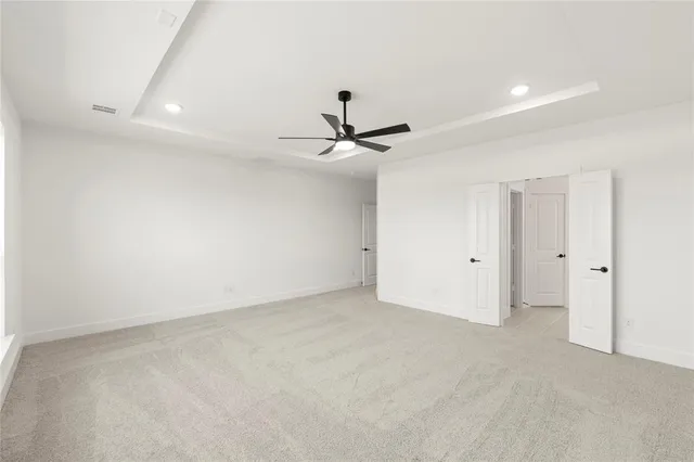 an empty room with windows and ceiling fan
