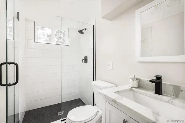 a bathroom with a granite countertop toilet sink and shower