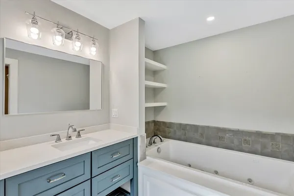 a bathroom with a tub a sink and mirror
