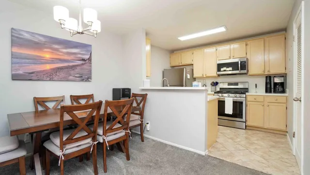 a kitchen with stainless steel appliances granite countertop a stove top oven a sink dishwasher a dining table and chairs with wooden floor