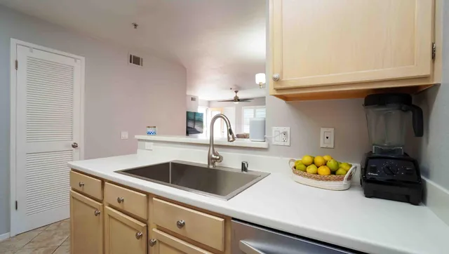 a kitchen with a sink and a stove with white cabinets