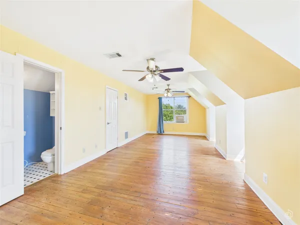 an empty room with wooden floor fan and windows