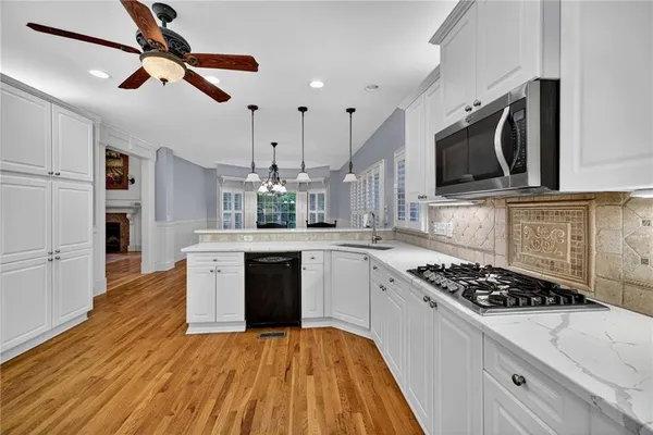 a kitchen with wooden floor a stove a sink and a microwave