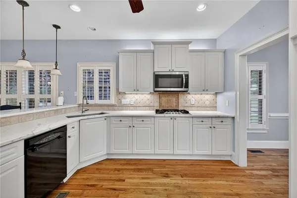 a kitchen with stainless steel appliances granite countertop a stove a sink cabinets and a wooden floor